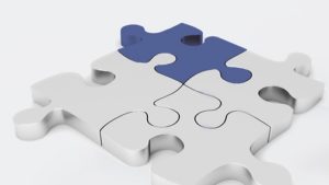 Abbildung eines Puzzles mit drei silbernen Teilen und einem blauen.