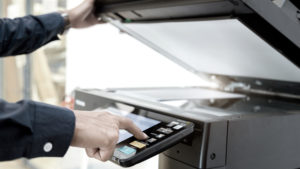 Aufgeklappter Drucker mit Hand, die auf das Drucker-Bedienpanel tippt